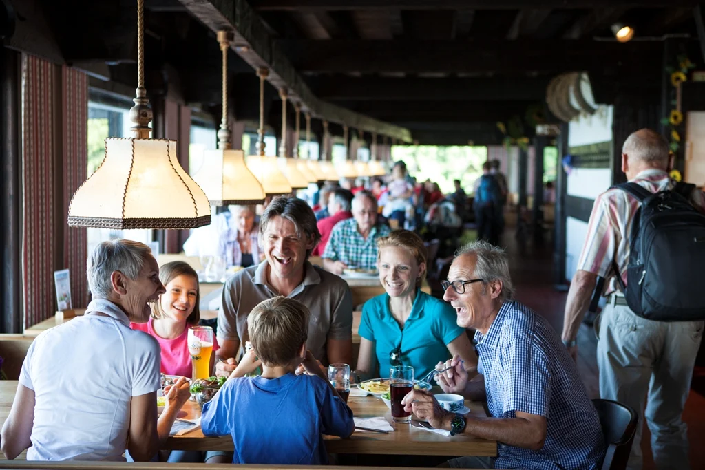 Familie sitzt beim Essen gemeinsam an einem Tisch im Restaurant Berghaus Pfänder