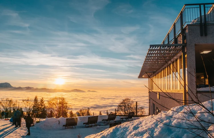 Ausblick vom Pfänder auf die umliegenden Berge an einem sonnigen Wintertag. Das Tal liegt unter einer Wolkendecke