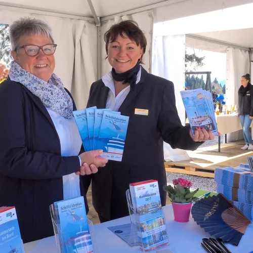 Zwei Frauen präsentieren Schifffahrtsprospekte auf Messe.