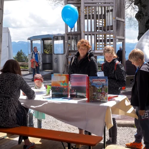 Menschen an einem Tisch mit Büchern und Ballon.