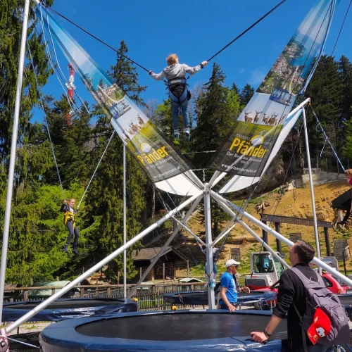 Person bungee springt auf Trampolin im Freien.