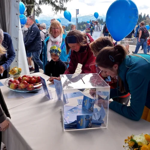 Menschen bei einer Veranstaltung mit blauen Luftballons.