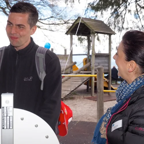 Personen unterhalten sich im Freien bei Spielplatz.