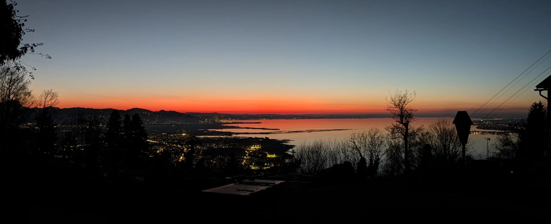 Sonnenuntergang am Pfänder mit Blick auf den Bodensee - der Himmel am Horizont leuchtet in organge/rot